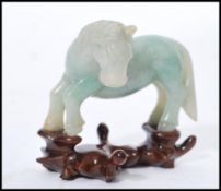 A vintage 20th century Chinese carved green jade figurine of a horse raised on carved wooden socle