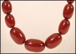 A vintage 20th century cherry amber bakelite necklace chain having 55 graduating beads with yellow