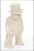 A 20th Century Bristol pottery figurine of Winston Churchill smoking a cigar having a cream glaze.