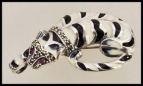 A silver brooch in the form of a cat having enamelled black and white colouring set with