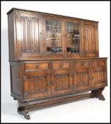 A Jaycee medium oak linen fold drawer dresser with lead glazed display cupboard flanked by carved