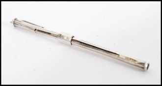 A sterling silver telescopic propelling pencil type toothpick and earwax scoop compendium on clip.