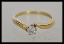 A hallmarked 18ct gold and solitaire crossover diamond ring, prong set with a brilliant cut diamond.