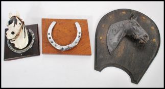 A vintage 20th Century cold cast bust of a horse set upon an ebonised horseshoe shapes oak back,