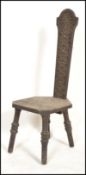 A Victorian carved oak Welsh spinning chair being raised on three legs with carved panel seat and