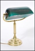 A 20th century brass bankers lamp raised on circular base with adjustable green glass shade. 36cm