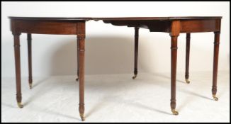 A George III mahogany crossbanded and inlaid extending d-end dining table. Raised on turned legs