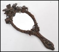 An early 20th century carved Black Forest hand mirror having shaped handle depicting birds. 35cm