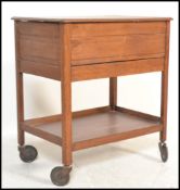 A mid century beech wood veneer sewing box cabinet set on to trolley wheels and raised on squared