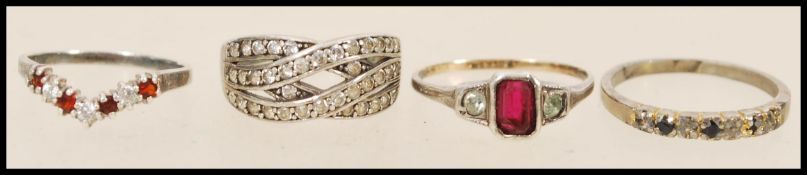 A group of four silver rings to include a crossover ring set with white stones, a wishbone ring