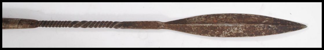 An early 20th century West African throwing spear having a wooden handle with metal twist binding.