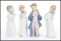 A group of four tall Lladro type Nao figurines to include Child with pillow and clock, Girl with
