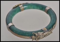 A 19th century Chinese jade bangle. The deep green jade bangle having silver white metal dragon