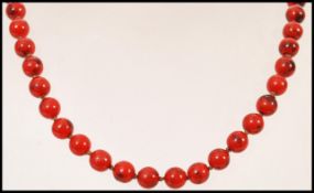 A vintage early 20th century red hardstone bead necklace having a gold claw clasp.