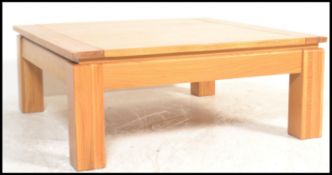A contemporary large oak coffee - occasional table of square form being raised on well turned legs
