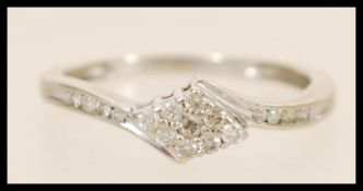 A stamped 375 9ct white gold crossover ring with a white stone cluster head and white accent