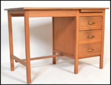 A 1970's teak wood writing table desk of Danish influence being raised on squared legs united by