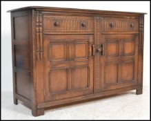 A 20th century Ercol ' Colonial ' beech and elm wood sideboard. The chamfered and flared edge top