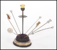 A collection of late 19th / early 20th Century hat pins, stored within a silver plated hat pin