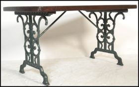 An early 20th century cast iron garden table having a painted scrolled cast iron base with wooden