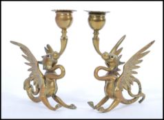 A pair of late 19th century cast brass candlesticks modelled as dragons with wings raised scrolled