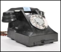 A vintage 1950's rotary bakelite telephone on a square base, having a pull out phone number tray,