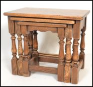 A 20th century oak nest of graduated tables by Jaycee, the flared tops raised on turned supports