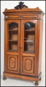 A 19th century walnut cabinet armoire bookcase raised on bun feet with twin glazed doors. Carved