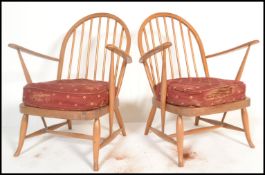 A pair of original mid 20th century Ercol Windsor pattern armchairs having shaped elbow supports