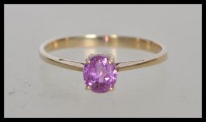 A stamped 375 9ct gold ring prong set with an oval cut central pink stone. Weight 1.7g. Size Q.