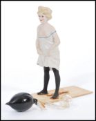 An early 20th century unusual bisque porcelain figurine of a nude lady urinating with remains of