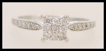 A stamped 375 white gold ring with a square head set with a cluster of white stones, and white