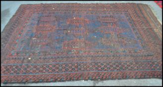 A late 19th / early 20th Century hand woven rug on red ground, geometric borders with a large
