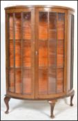 A 1930's Art Deco walnut demi lune display cabinet being raised on cabriole legs with pad feet