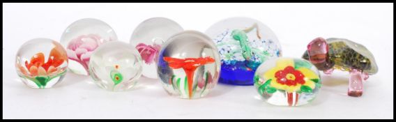 A selection of 20th century glass domed paper weights having glass flowers to the interior, a long