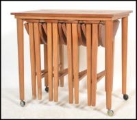 A 1970's retro teak wood quartetto nest of tables raised on turned legs with a series of tables to
