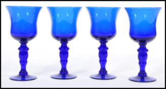 A set of four unsigned Bristol Blue glass goblet wine glasses raised on circular bases with baluster