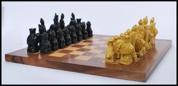 A 20th Century chess set made of contrasting stained wood, having Chinese resin figures with foo dog