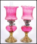 A pair of 19th Century Victorian oil lamps having cranberry glass shades with fanned rims and