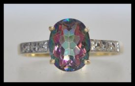A stamped 375 9ct gold ring set with an oval cut purple and green iridescent stone and white