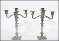 A matching set of three silver plated candelabras raised on square bases with scrolled arms and
