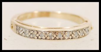 A 9ct gold ladies ring set with white accent stones to the band and a hidden hinged section to the