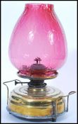 A 19th Century Victorian oil lamp having a large round brass base with handles to either side raised