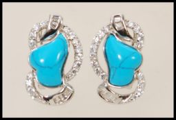 A pair of silver stud earrings set with turquoise stones and cubic zirconia.