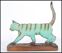 A vintage 20th century folk art painting on metal sculpture of a cat being raised on a live edge