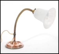 A vintage retro 20th century industrial copper gooseneck desk lamp raised on a circular base with