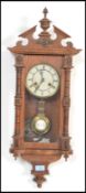 A Vienna-styled wall clock, oak case with opening glazed door flanked by turned decoration,