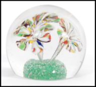 A 20th century domed spherical form glass paperweight with three flowers on a green ground to the