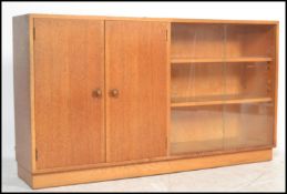 A vintage retro oak side board having two cupboard doors next to a shelved section having sliding