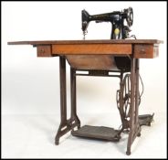An early 20th century Singer treadle sewing machine table having a cast and wrought iron pedestal
